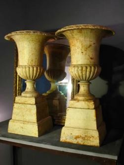 PAIR OF FRENCH PAINTED CAST IRON URNS ON PLINTHS